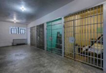 Interior view of a prison cell block with metal bars and concrete flooring