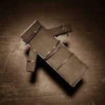 Cardboard figure bound with rubber bands on a dark surface