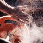 Athlete’s chalked hands above an orange weight plate