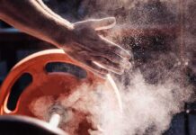Athlete’s chalked hands above an orange weight plate