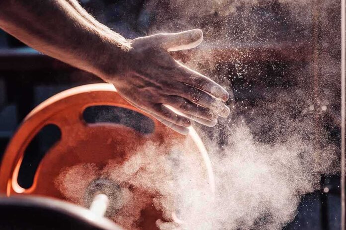 shutterstock_644235430 Athlete’s chalked hands above an orange weight plate